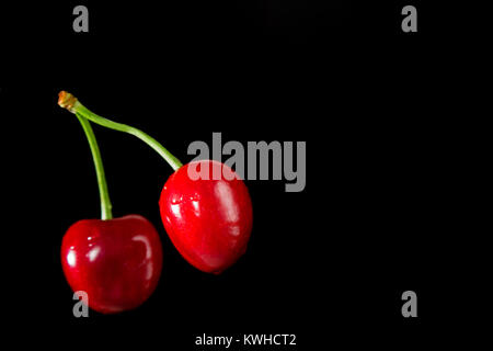 Mature ciliege rosse su uno sfondo nero. Messa a fuoco selettiva Foto Stock