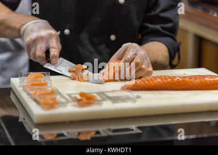 Le mani per affettare il salmone salato in un ristorante closeup Foto Stock
