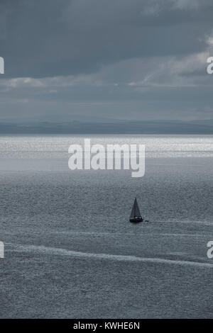 Una solitaria vela yacht oriente fuori in Brodick Bay, Isle of Arran, Scozia. Foto Stock