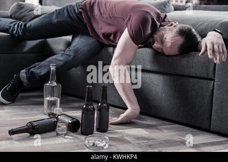 Ubriaco uomo barbuto in appoggio sul divano Foto Stock