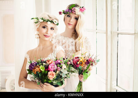 Due perfetti sposa. Donna bionda con fiori e ghirlande di fiori, nozze acconciatura e trucco Foto Stock