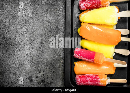 Multicolore di ghiaccio di frutta fatta da frutti. Su uno sfondo rustico. Foto Stock