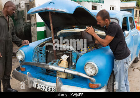 Uomo cubano ripara il suo blu vintage Buick auto presso la stazione di gas in Santa Clara Cuba - Serie Cuba Reportage Foto Stock