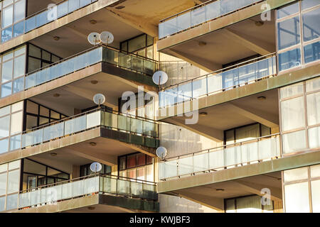 La facciata dell'edificio reseidential con finestre e balconi e antenne satellitari Foto Stock