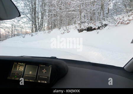 Non trattate scivoloso ghiaccio coperto di neve alpina francese country road, con ghiaccio, visibile attraverso il parabrezza dall'interno dell'auto al tramonto. Alta Savoia, Francia Foto Stock