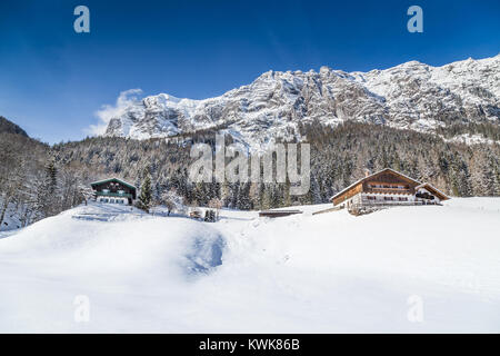 Vista panoramica della splendida winter wonderland paesaggio di montagna delle Alpi con un tradizionale chalet di montagna in una fredda giornata di sole con cielo blu e clo Foto Stock