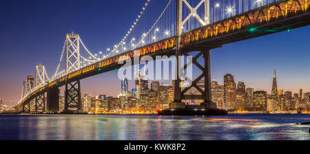 Classic vista panoramica del famoso Oakland Bay Bridge con lo skyline di San Francisco illuminata nella bellissima twilight dopo il tramonto in estate, Califo Foto Stock