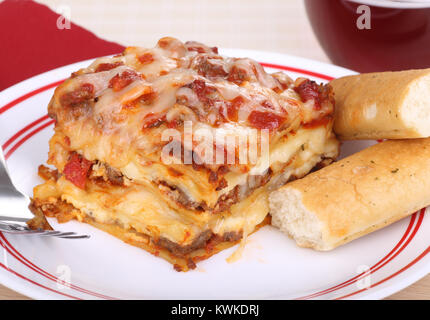 Pezzo di lasagne con bastoncini di pane su una piastra Foto Stock