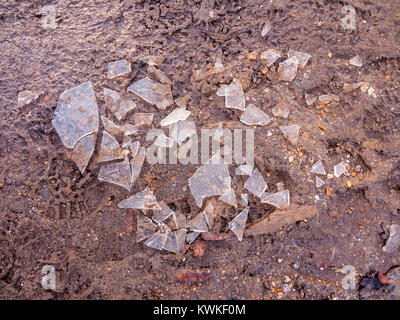 In frantumi rotto il ghiaccio sul pavimento di fango a piedi al di fuori della superficie texture gelo invernale; essex; Inghilterra; Regno Unito Foto Stock