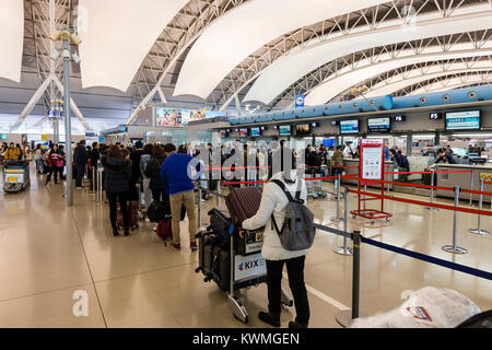 Giappone, Kansia aeroporto, interno. Partenza internazionale check-in zona. Code di persone, principalmente asiatici, in attesa di effettuare il check-in presso i banchi check-in durante il periodo di punta dopo tre giorni di nuovo anno di vacanza. Foto Stock