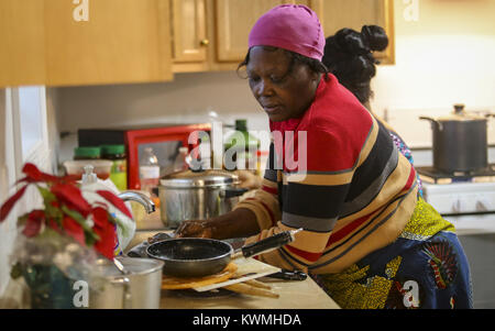 Davenport, Iowa, USA. 25 Dic, 2016. Anoko Lawson lava stoviglie a suo figlio della casa di Davenport, domenica 25 dicembre, 2016. La famiglia, originariamente da ovest nazione africana del Togo, spostati nella loro nuova casa costruita da Habitat per l'umanità il 14 dicembre. Credito: Andy Abeyta/Quad-City volte/ZUMA filo/Alamy Live News Foto Stock