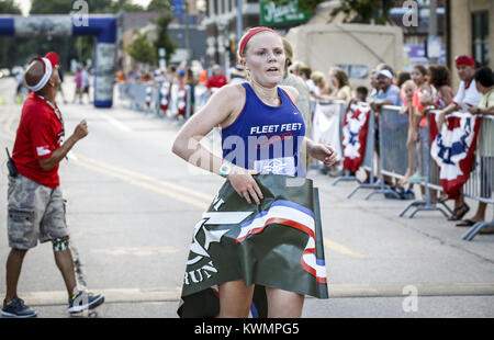 Davenport, Iowa, USA. Il 4° agosto 2016. Kelsey Allbaugh di Bettendorf è la prima donna a tagliare il traguardo della 5k libertà eseguire in fabbrica East Moline giovedì 4 agosto, 2016. La libertà eseguire 5k, che presentava un capretto ostacolo e un miglio di gara nonché il 5k stesso, si è svolta nel centro di East Moline come un vantaggio ai militari locali le famiglie. Credito: Andy Abeyta/Quad-City volte/ZUMA filo/Alamy Live News Foto Stock