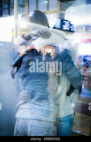 Coppia giovane in amore abbracciando all'arrivo o di partenza in un moderno aeroporto internazionale Foto Stock