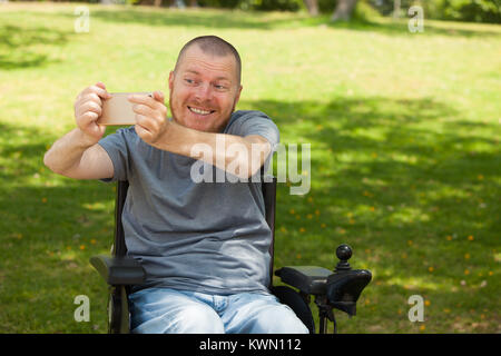 Uomo disabili in sedia a rotelle facendo selfie Foto Stock