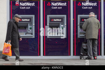 Titolare di una pensione o di una rendita utilizzando un punto di contanti macchina a NatWest Bank in Southampton High Street, Regno Unito Foto Stock