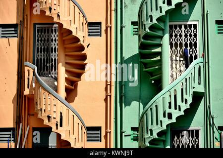 Una coppia di colorata vecchia pietra scale a spirale sulla superficie esterna del negozio a schiera case nel centro storico di Little India, Singapore Foto Stock