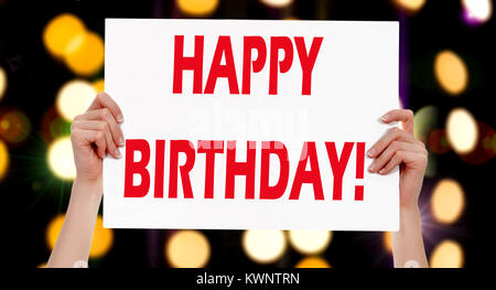 Buon compleanno! Mani femminili tenendo un cartello con luci astratta sfondo bokeh di fondo Foto Stock