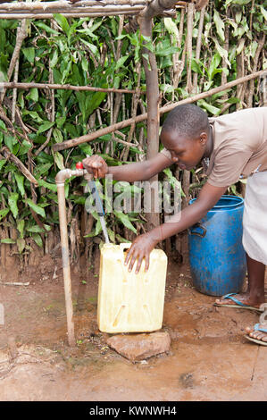 Bambino ruandese raccogliendo un contenitore di acqua da un tubo di supporto in acqua nuova iniziativa Foto Stock