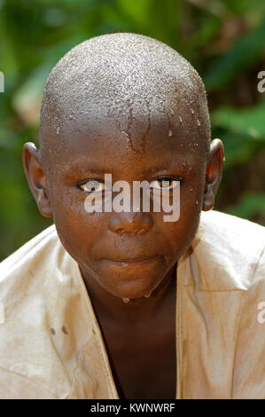 Ragazzo ruandese lavando il suo volto in acqua pulita. Foto Stock