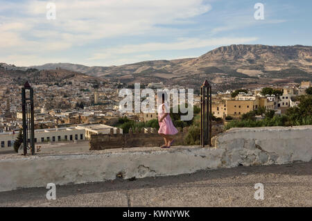 Un bambino che gioca su una parete sopra la città di Fez, Marocco, Africa del Nord Foto Stock