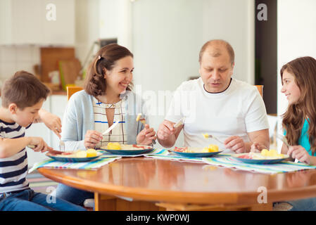 Felice la grande famiglia di gustare la cena in casa. Madre, padre e figlia, figlio Foto Stock