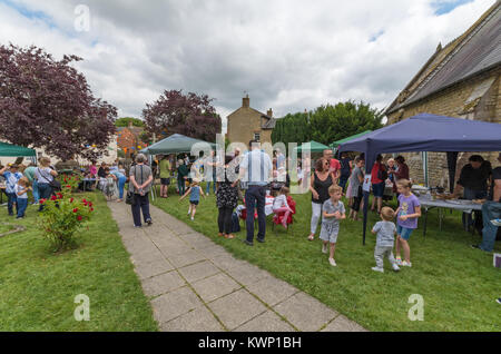 Una folla di gente che incontro presso una chiesa fete nel villaggio di Bromsgrove, Northamptonshire, Regno Unito Foto Stock