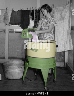 Donna abiti di lavaggio con un antico torcenti di macchina di lavaggio circa 1939. Foto Stock
