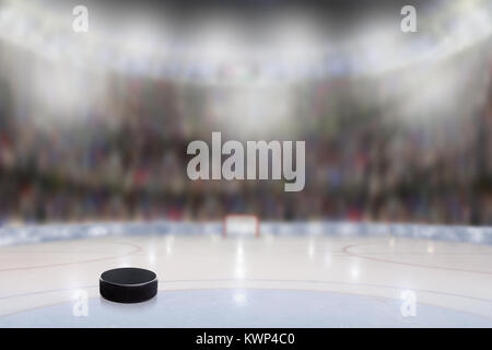 Basso angolo vista di hockey su ghiaccio puck su ghiaccio con la deliberata profondità di campo sulla luminosa stadium di sfondo e copiare lo spazio. Foto Stock