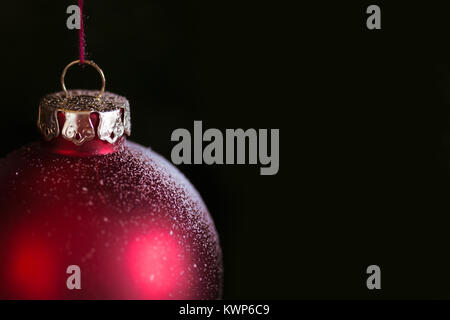 Orizzontale vista frontale ravvicinata di un natale rosso globe appeso con copyspace nera sulla destra Foto Stock