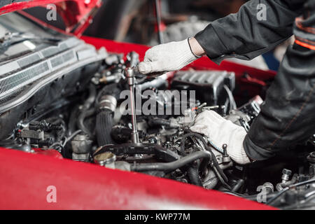 La riparazione dei moderni motori diesel, lavoratori mani e strumento. Close-up di un'auto meccanico che lavora su una vettura a motore Foto Stock