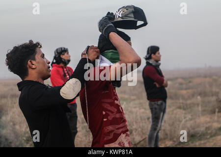 Un gruppo di giovani palestinesi nella striscia di Gaza si alzano in piedi davanti al recinto di separazione con Israele Solidarietà con Gerusalemme contro Trump per la decisione di dichiarare Foto Stock