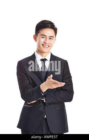 Giovane imprenditore asiatico rendendo un invito, guardando la telecamera sorridendo, isolato su sfondo bianco. Foto Stock