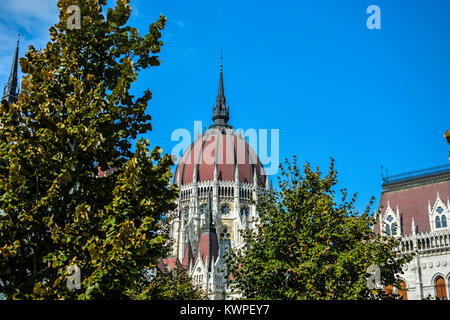 La cupola del parlamento ungherese edificio Ungherese di Budapest in una giornata di sole a inizio autunno con alberi in primo piano Foto Stock