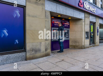 Un cliente a ritirare il denaro presso la Nat West Bank macchina bancomat (ATM), Market Street, Huddersfield, West Yorkshire. Foto Stock