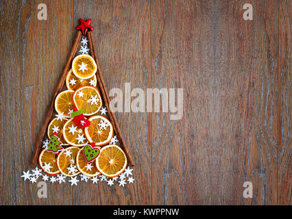 Albero di natale di fettine di arancia, fiocchi di neve e le decorazioni di Natale su sfondo di legno. Natale, inverno, anno nuovo concetto. Vista dall'alto. Foto Stock