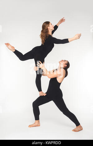 Giovane adulto giovane facendo acroyoga pongono per la pratica in equilibrio. Studio shot, isolato su sfondo bianco Foto Stock