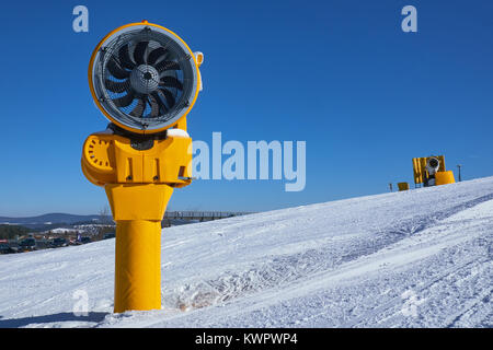 Due spento giallo cannoni da neve su una pista a carosello sciistico Winterberg contro un cielo blu chiaro Foto Stock