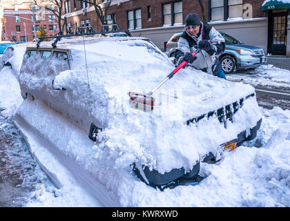 New York, Stati Uniti d'America. Gen 5, 2018. Un residente cancella la sua coperta di neve auto a New York del lato est superiore dopo un 'bombogenesis' o 'bomba ciclone' Blizzard ha portato un record neve, freddo pungente e venti forti sulla città. Credito: Enrique Shore/Alamy Live News Foto Stock