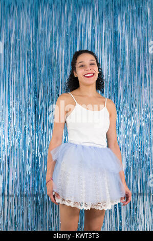 Adolescente brasiliana è sorridente. Capelli ricci la donna è vestita come una ballerina. Uscire tutu. Sfondo colorato. Concetto di celebrazione, Carnevale, nuovo Y Foto Stock