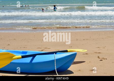 Blue canoa kayak su una spiaggia con le onde e le persone, Bagal spiaggia vicino a Townsville, Queensland, Australia Foto Stock