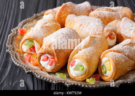 Cannoli dolce farcito con crema di formaggio e frutta candita close-up su una piastra su un piano orizzontale. Foto Stock