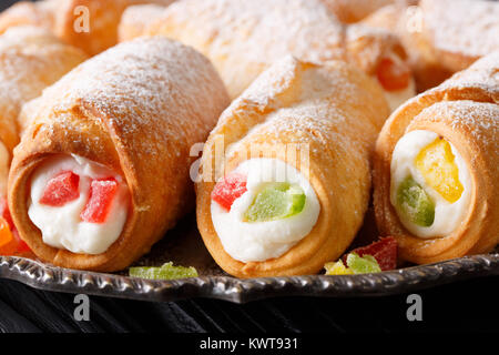 Italiani dolci cannoli con crema di formaggio e frutta candita macro su una piastra orizzontale. Foto Stock