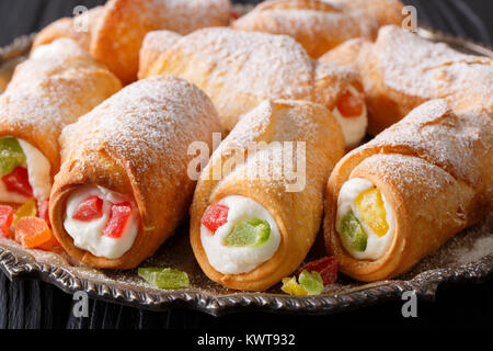 Cottura siciliana cannoli con crema di formaggio e frutta candita macro su una piastra orizzontale. Foto Stock