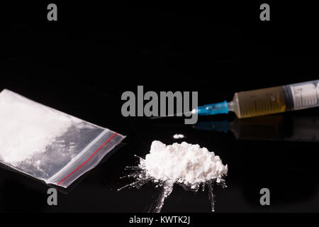 La cocaina, Herion o altre droghe illegali che vengono rilevati per mezzo di un tubo o iniettato con una siringa isolato nero su sfondo lucido Foto Stock