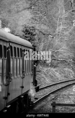 Ritratto, Black & White shot motore inclinazione pilota al di fuori della cabina di vintage locomotiva a vapore, in azione sul Severn Valley Railway linea Heritage. Foto Stock