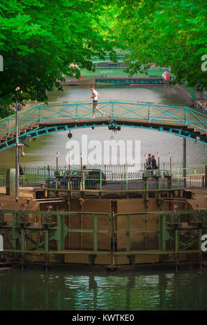 Uomo jogging Parigi, vista in tarda primavera di un giovane uomo che corre attraverso un ponte sul Canal Saint-Martin nel centro di Parigi, Francia. Foto Stock