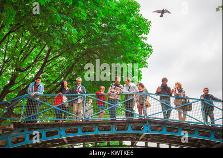 Parigi Canal Saint Martin, turisti guardare da un ponte come una barca che attraversa un blocco al di sotto di esse sul Canal Saint-Martin nel centro di Parigi, Francia. Foto Stock