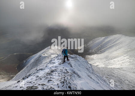 Walker discendente della hall è caduto sulla cresta Blencathra nella neve, Lake District, Cumbria, Regno Unito Foto Stock