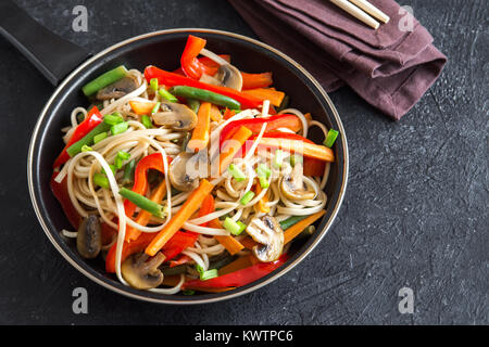 Stir fry con udon tagliatelle, funghi e ortaggi. Asian vegane cibo vegetariano, pasto, STIR FRY su sfondo nero, copia dello spazio. Foto Stock