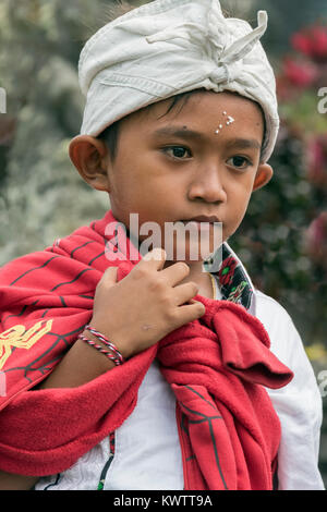 Ragazzo con wet chicchi di riso sulla sua fronte, Pura Besakih Temple, Monte Agung, Bali, Indonesia Foto Stock